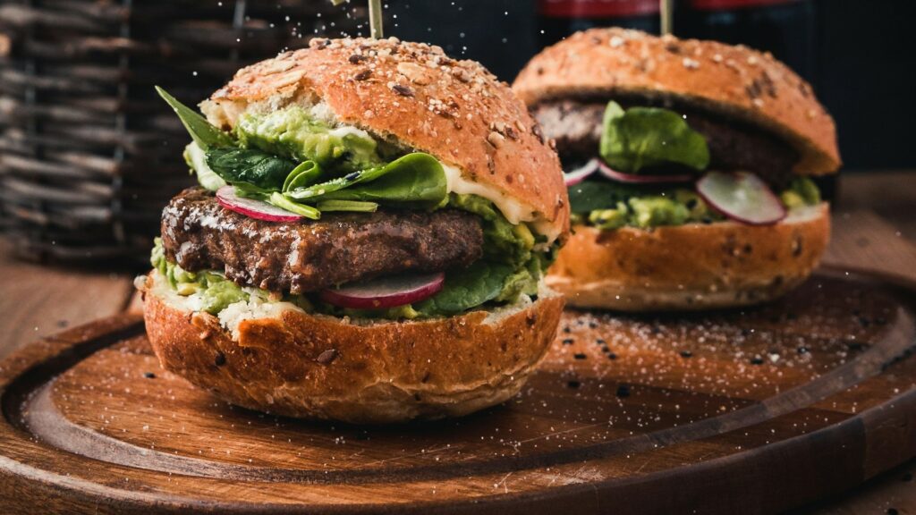 burger being salted on a wooden platter