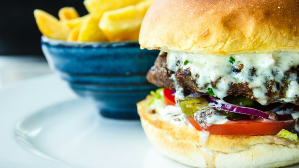 close up of a juicy burger and a bowl of chips