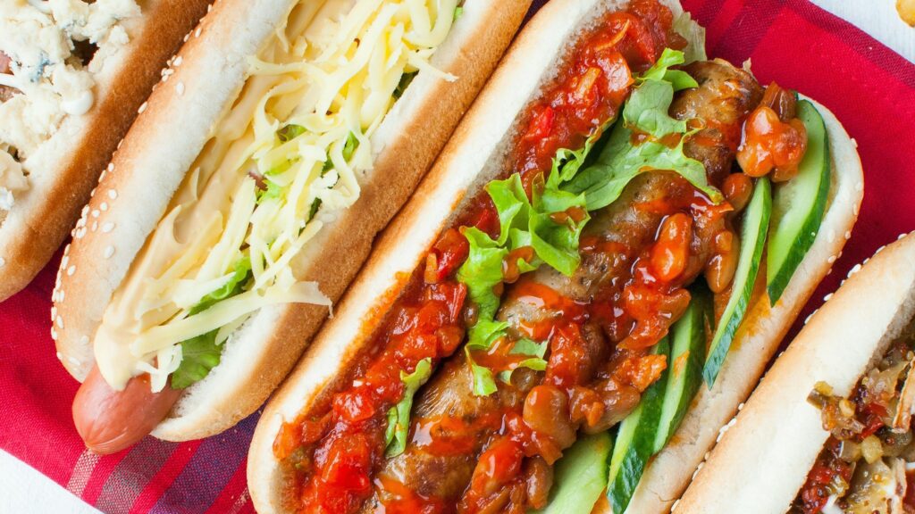 close up of a variety of different hot dogs on a red blanket