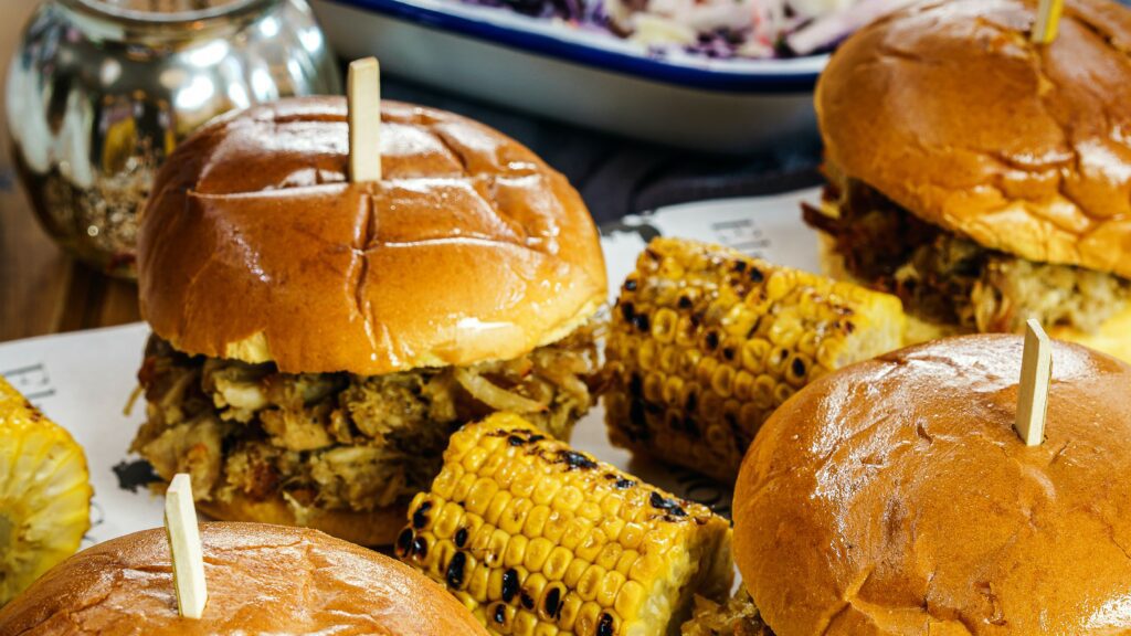 smash burgers and corn on the cob on a table