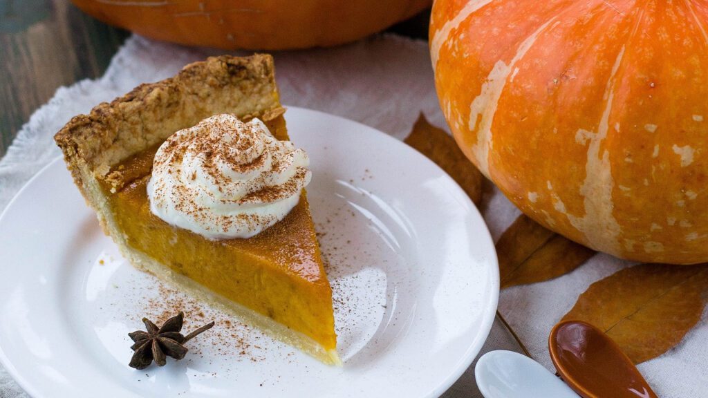 pumpkin pie slice on a plate near pumpkins 1920 x 1080