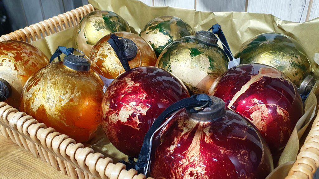 Glass Christmas baubles in a basket multicoloured