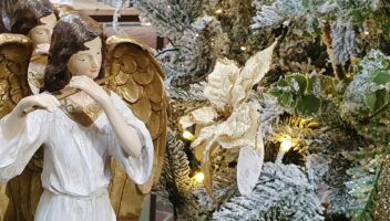 angels and a poinsettia near a snowy christmas tree