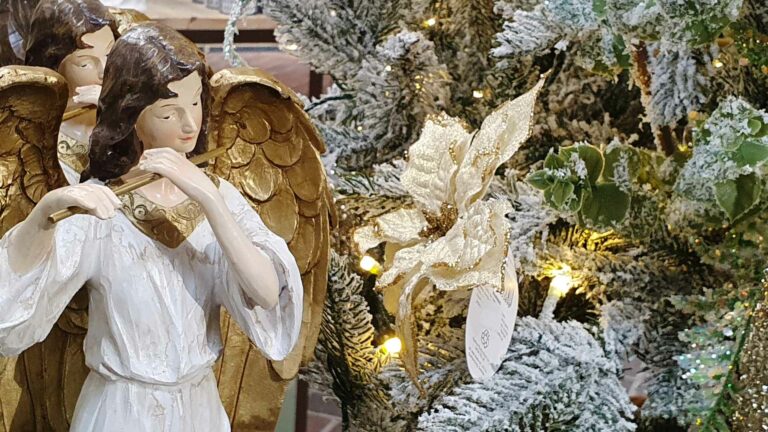 angels and a poinsettia near a snowy christmas tree