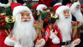 traditional christmas santa figures standing and holding a present